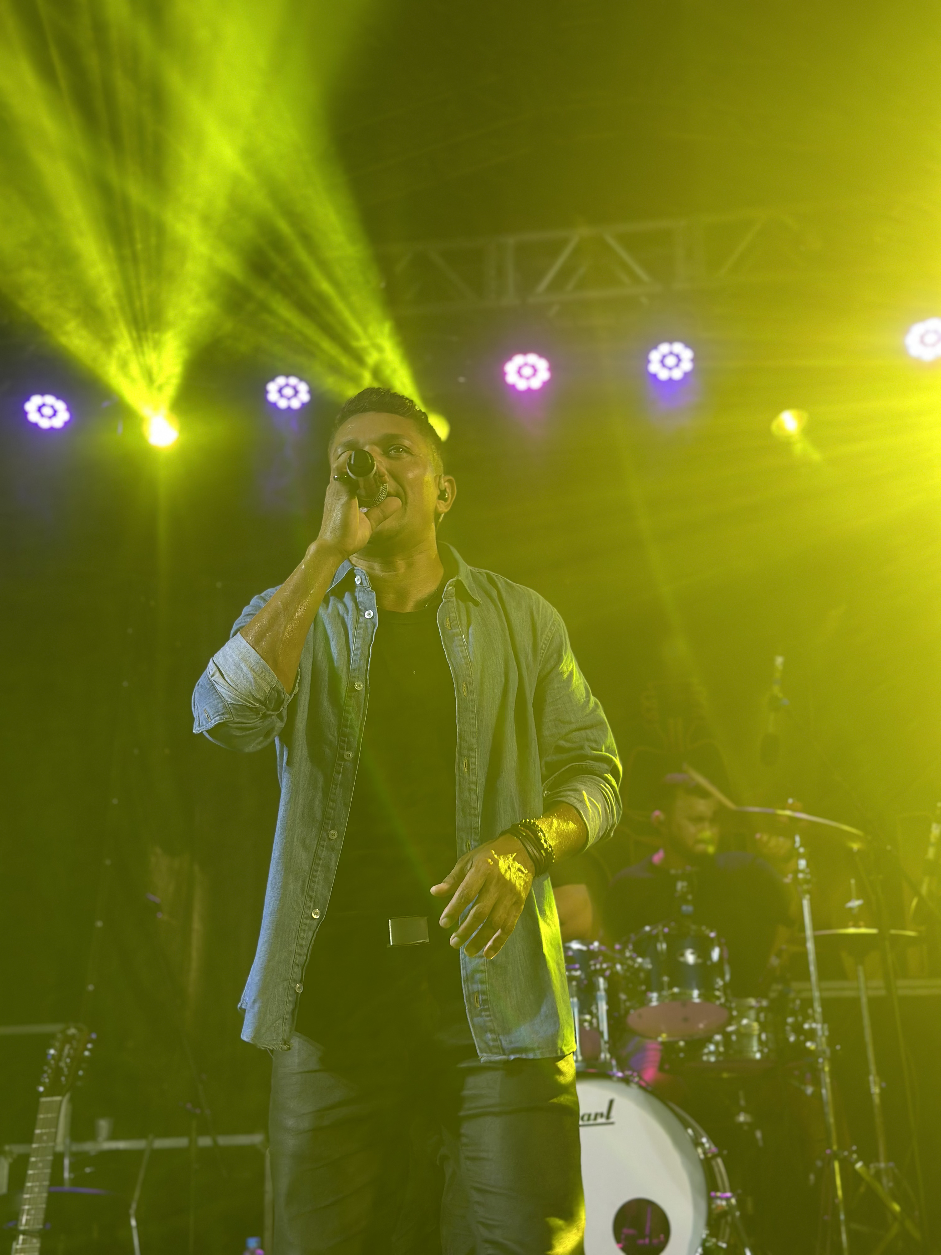 Ronan Andrade cantando no palco com iluminação dourada